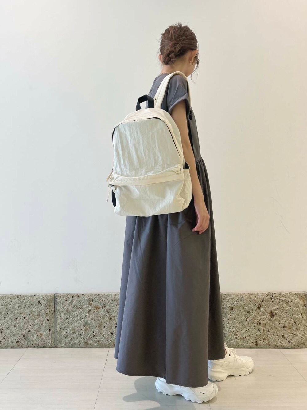 ホワイト系のバックパック/リュック、ホワイト系のスニーカー、グレー系のワンピースを着用したレディースの夏コーディネートの5枚目の写真