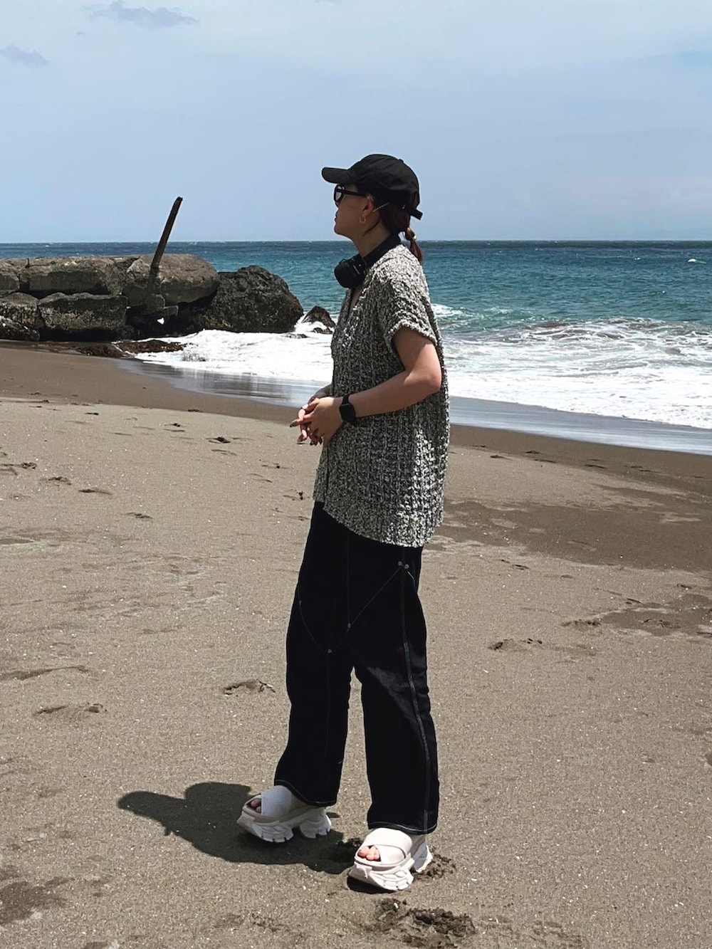 グレー系のタンクトップ、ブルー系のデニムパンツ、ブラウン系のドラムバッグを着用したレディースの春コーディネートの2枚目の写真