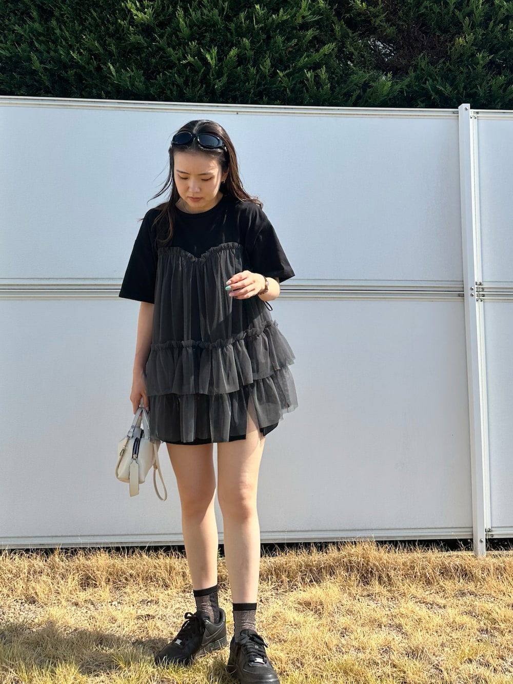 ブラック系のTシャツ/カットソー、ホワイト系のショルダーバッグ、ブラック系のサングラスを着用したレディースの夏コーディネートの2枚目の写真