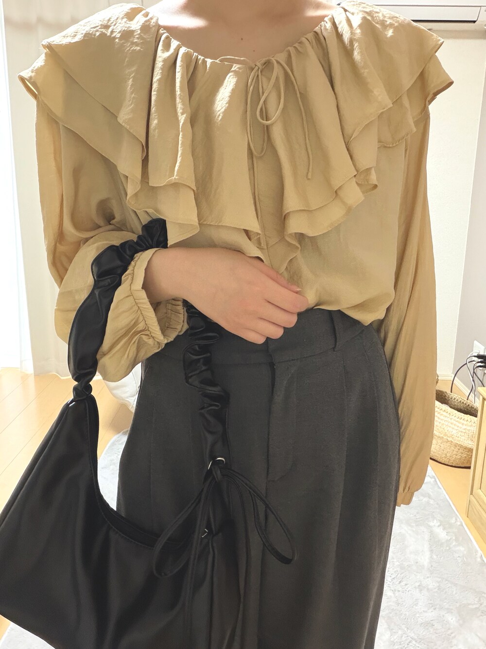 イエロー系のトップス、グレー系のパンツ、ブラック系のバッグを着用したレディースの春コーディネートの3枚目の写真