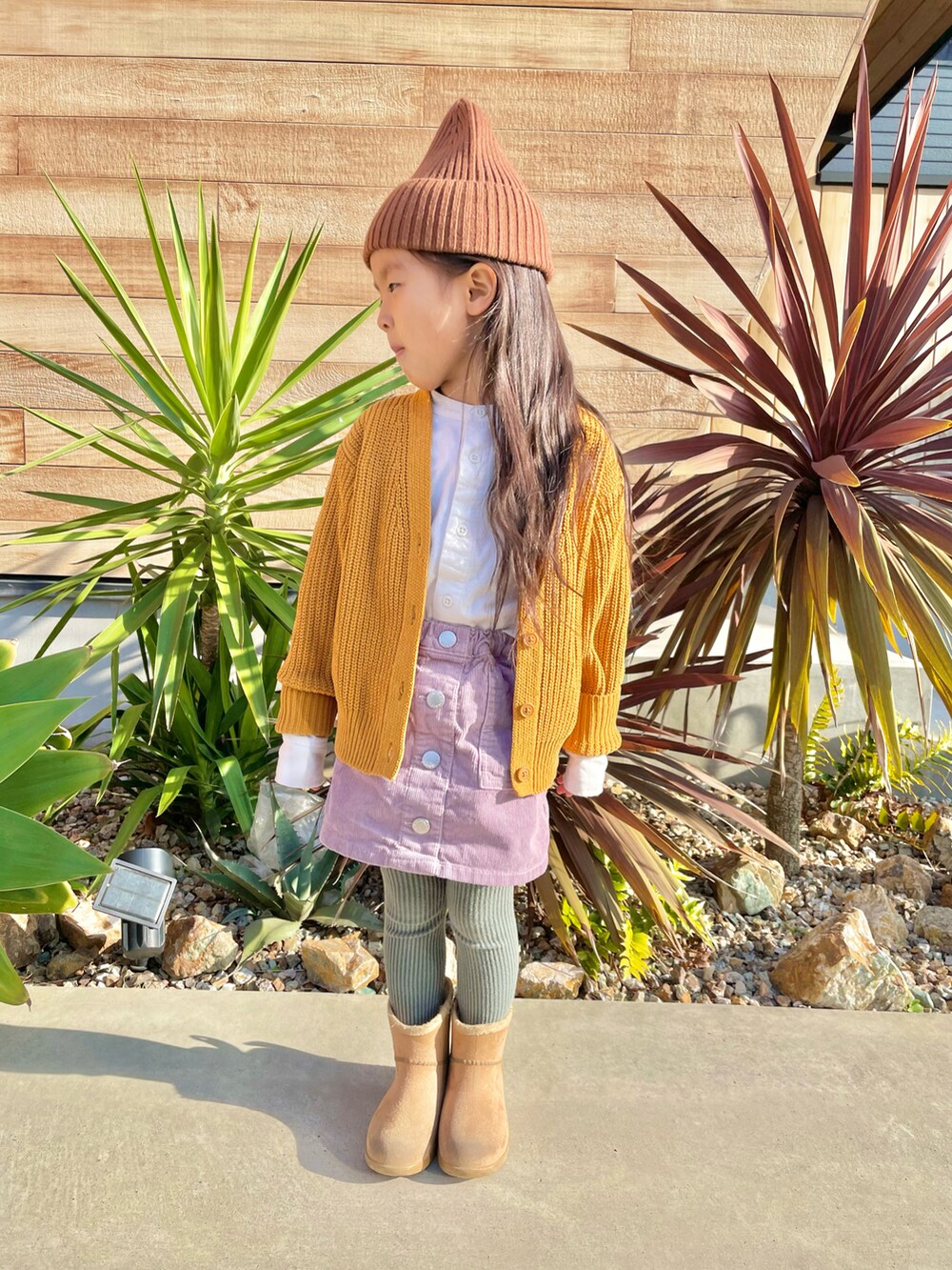 ブラウン系のカーディガン/ボレロ、ホワイト系のシャツ/ブラウス、パープル系のスカートを着用したキッズの冬コーディネートの2枚目の写真