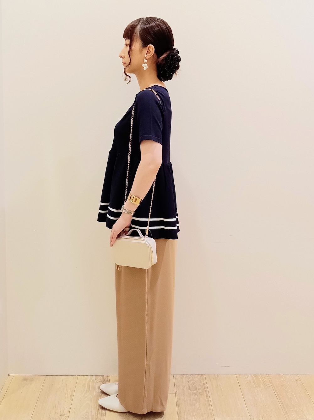 ブルー系のニット/セーター、ベージュ系のその他パンツ、ホワイト系のショルダーバッグを着用したレディースの夏コーディネートの3枚目の写真