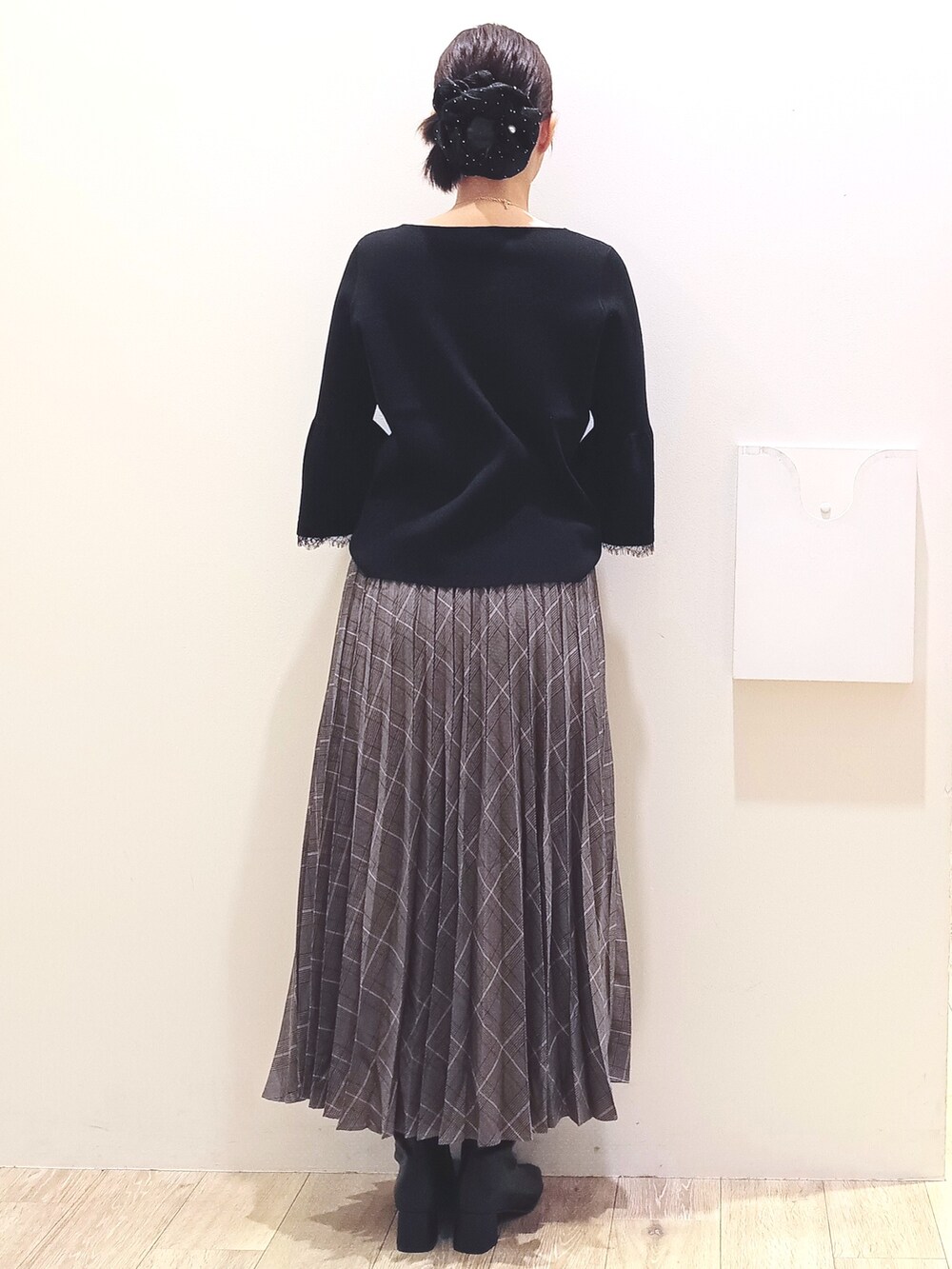 ブラック系のニット/セーター、グレー系のスカート、ベージュ系のショルダーバッグを着用したレディースの秋コーディネートの5枚目の写真
