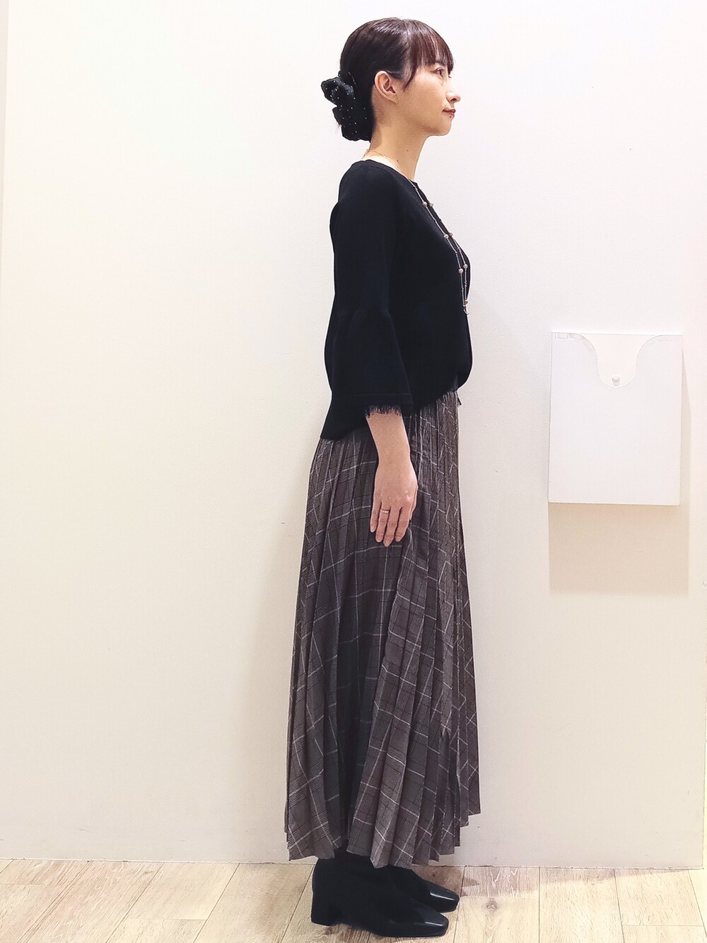 ブラック系のニット/セーター、グレー系のスカート、ベージュ系のショルダーバッグを着用したレディースの秋コーディネートの3枚目の写真