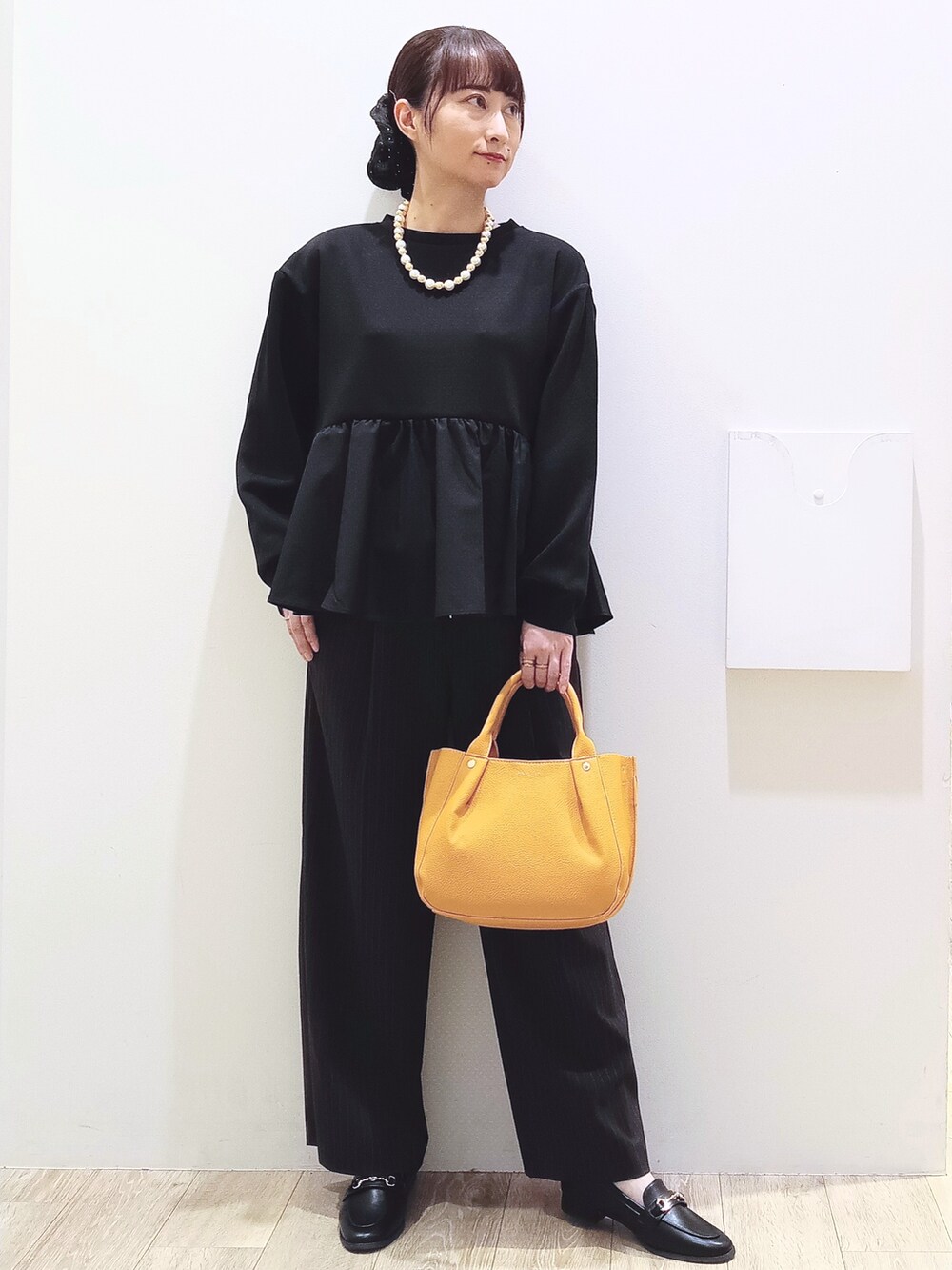 ブラック系のTシャツ/カットソー、ブラウン系のその他パンツ、イエロー系のトートバッグを着用したレディースの秋コーディネートの2枚目の写真