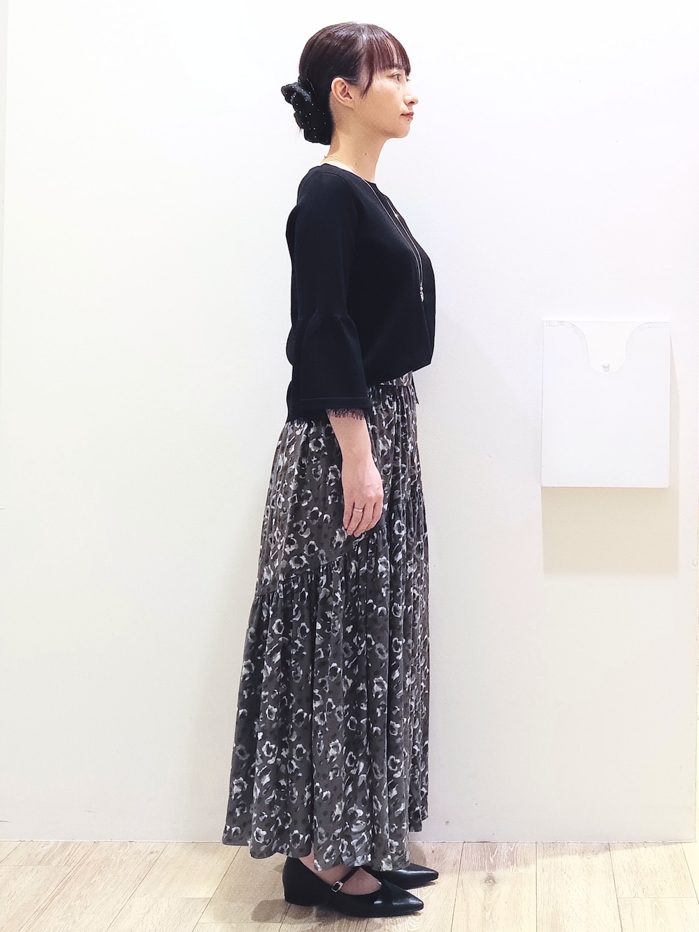 ブラック系のニット/セーター、グレー系のスカート、ホワイト系のハンドバッグを着用したレディースの秋コーディネートの4枚目の写真