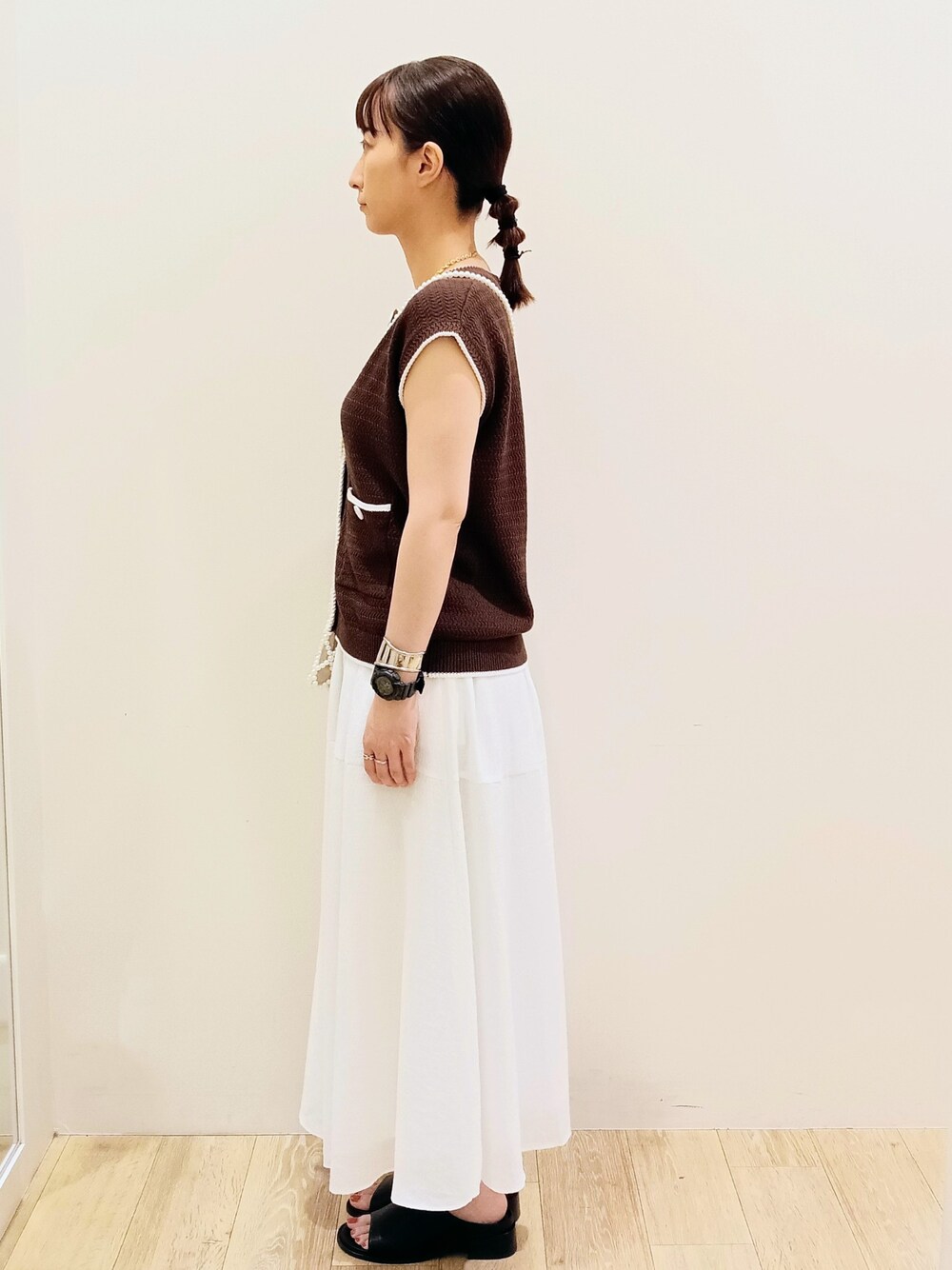 ブラウン系のベスト、ホワイト系のタンクトップ、ホワイト系のスカートを着用したレディースの夏コーディネートの3枚目の写真