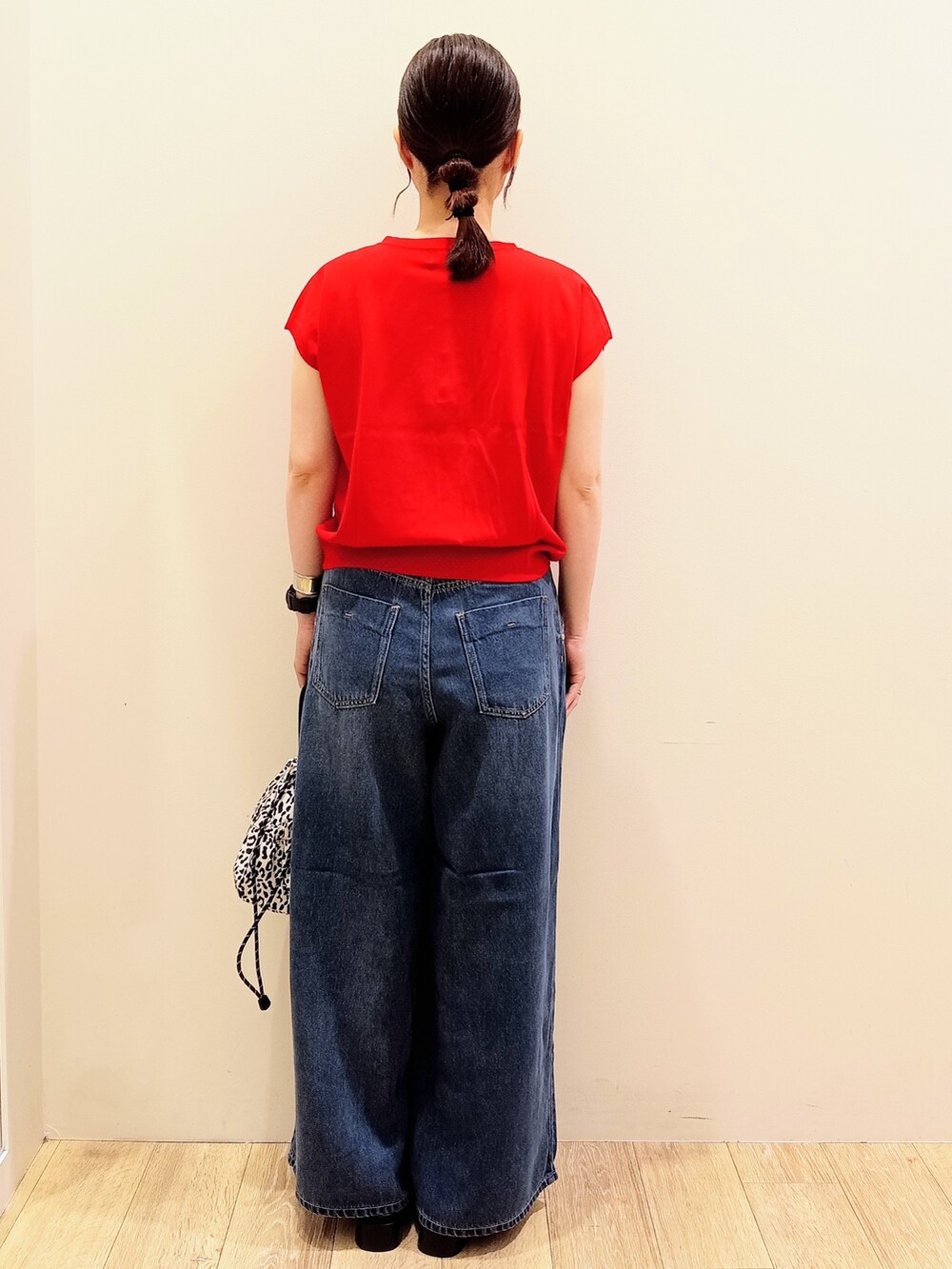 レッド系のニット/セーター、ブラック系のタンクトップ、ブルー系のデニムパンツを着用したレディースの夏コーディネートの5枚目の写真
