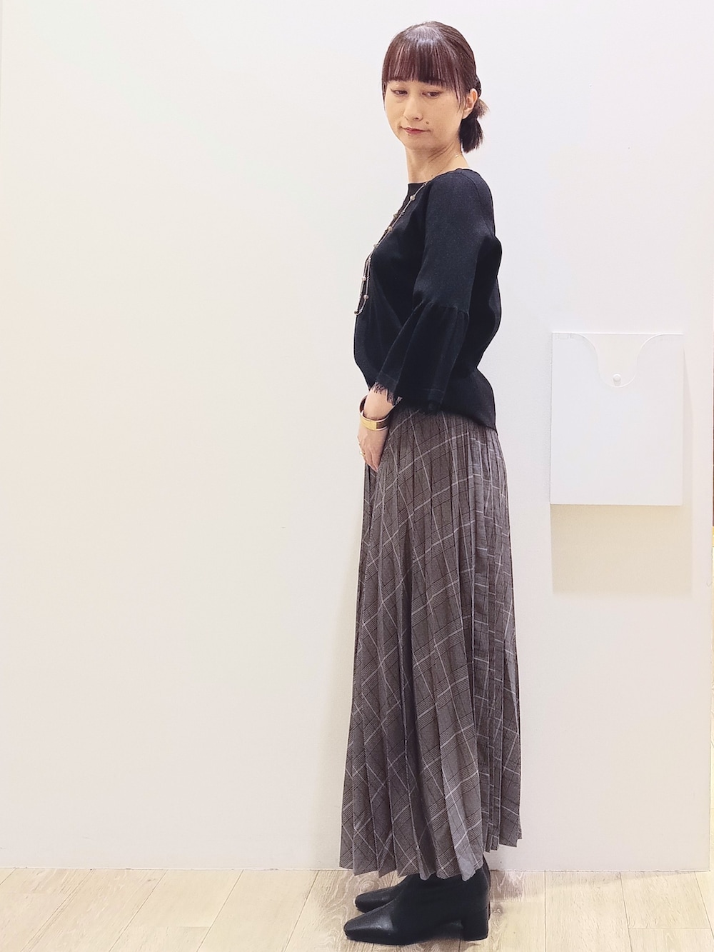 ブラック系のニット/セーター、グレー系のスカート、ベージュ系のショルダーバッグを着用したレディースの秋コーディネートの4枚目の写真