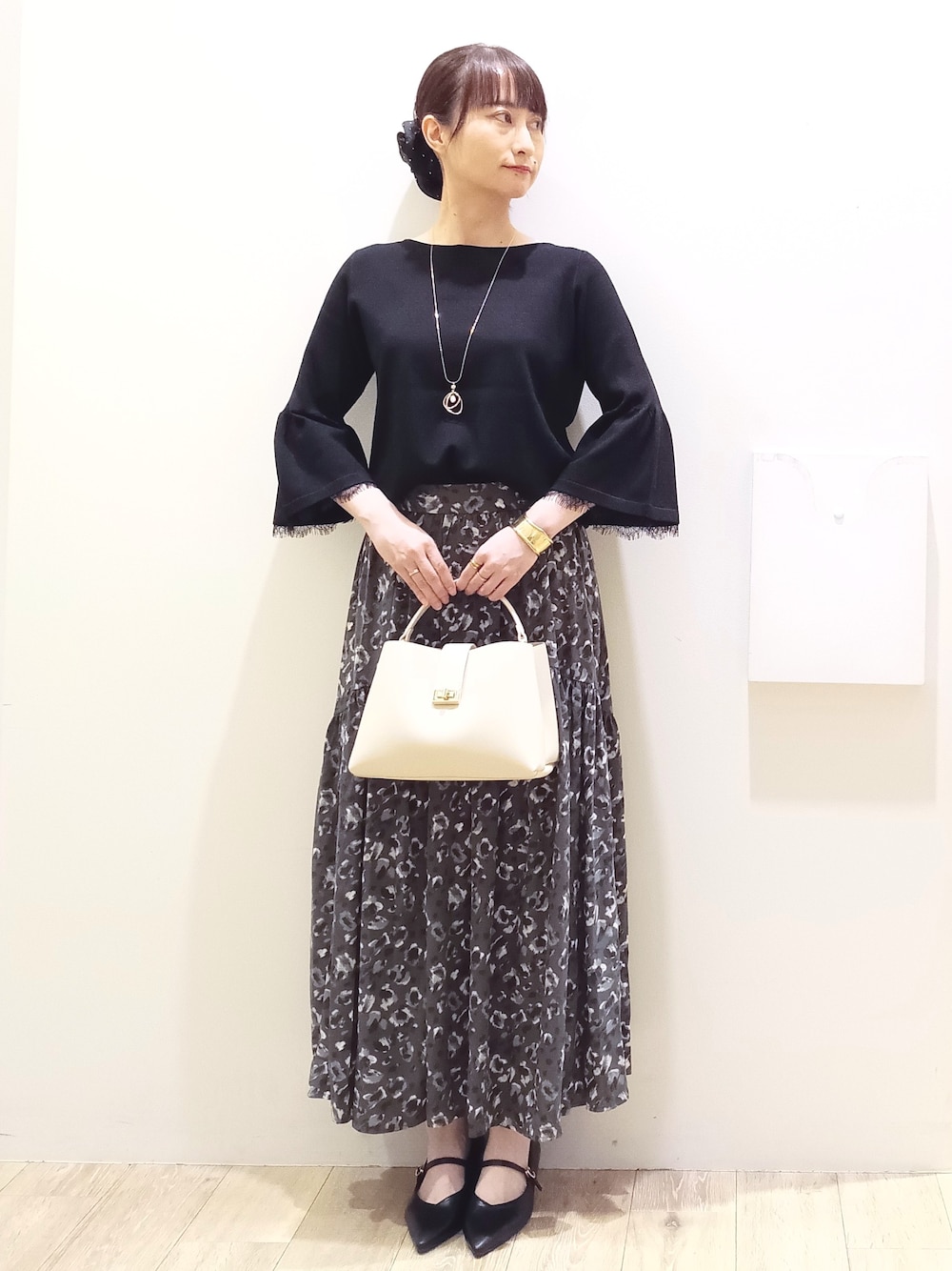 ブラック系のニット/セーター、グレー系のスカート、ホワイト系のハンドバッグを着用したレディースの秋コーディネートの2枚目の写真