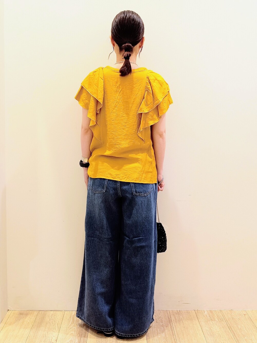 イエロー系のシャツ/ブラウス、ブルー系のデニムパンツ、ブラック系のショルダーバッグを着用したレディースの夏コーディネートの5枚目の写真