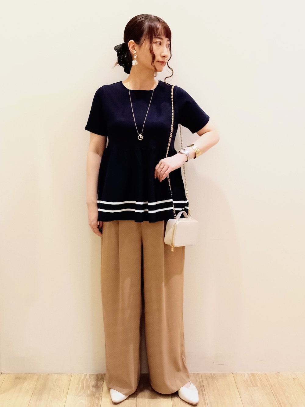 ブルー系のニット/セーター、ベージュ系のその他パンツ、ホワイト系のショルダーバッグを着用したレディースの夏コーディネートの2枚目の写真