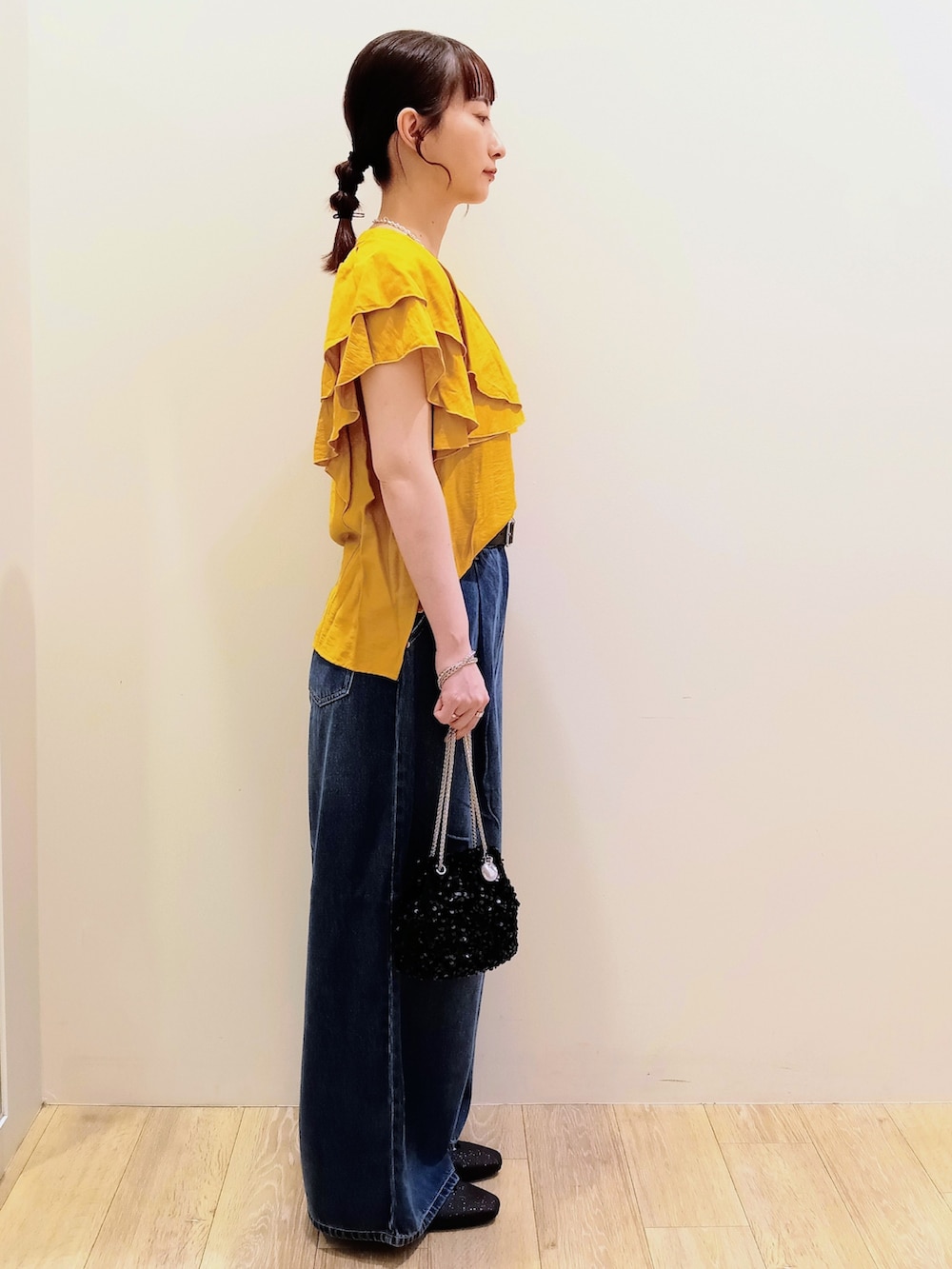 イエロー系のシャツ/ブラウス、ブルー系のデニムパンツ、ブラック系のショルダーバッグを着用したレディースの夏コーディネートの4枚目の写真