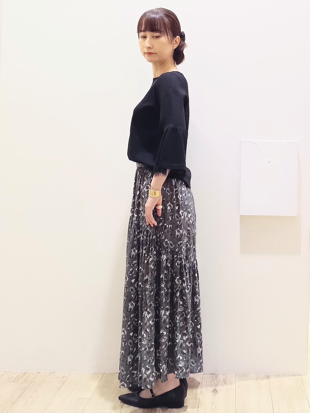 ブラック系のニット/セーター、グレー系のスカート、ホワイト系のハンドバッグを着用したレディースの秋コーディネートの5枚目の写真