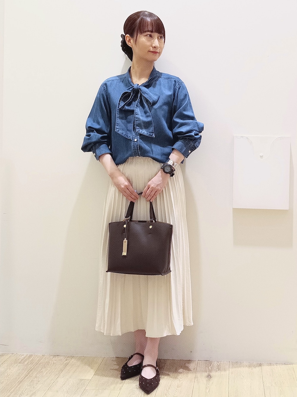ブルー系のシャツ/ブラウス、ホワイト系のスカート、ブラウン系のトートバッグを着用したレディースの秋コーディネートの2枚目の写真
