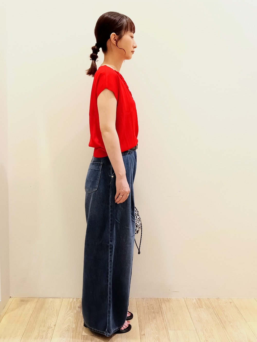 レッド系のニット/セーター、ブラック系のタンクトップ、ブルー系のデニムパンツを着用したレディースの夏コーディネートの4枚目の写真