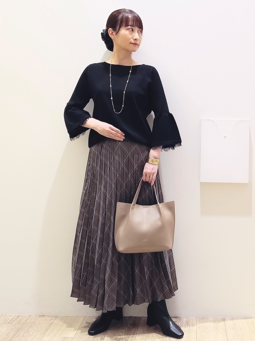 ブラック系のニット/セーター、グレー系のスカート、ベージュ系のショルダーバッグを着用したレディースの秋コーディネートの2枚目の写真