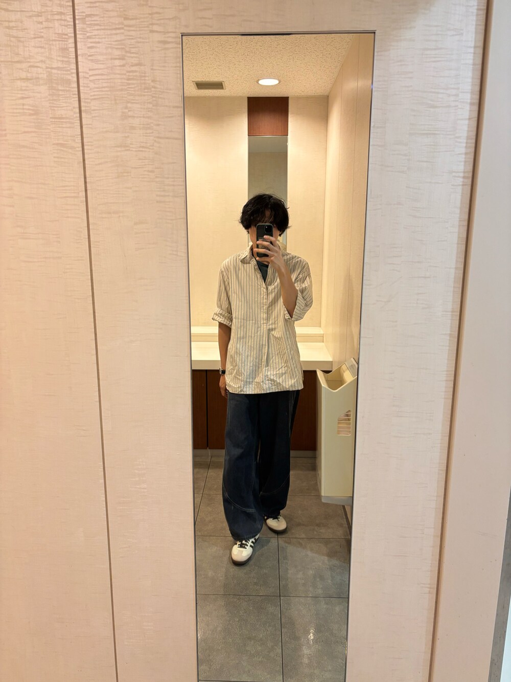 ブルー系のデニムパンツ、ベージュ系のスニーカーを着用したメンズの夏コーディネートの2枚目の写真