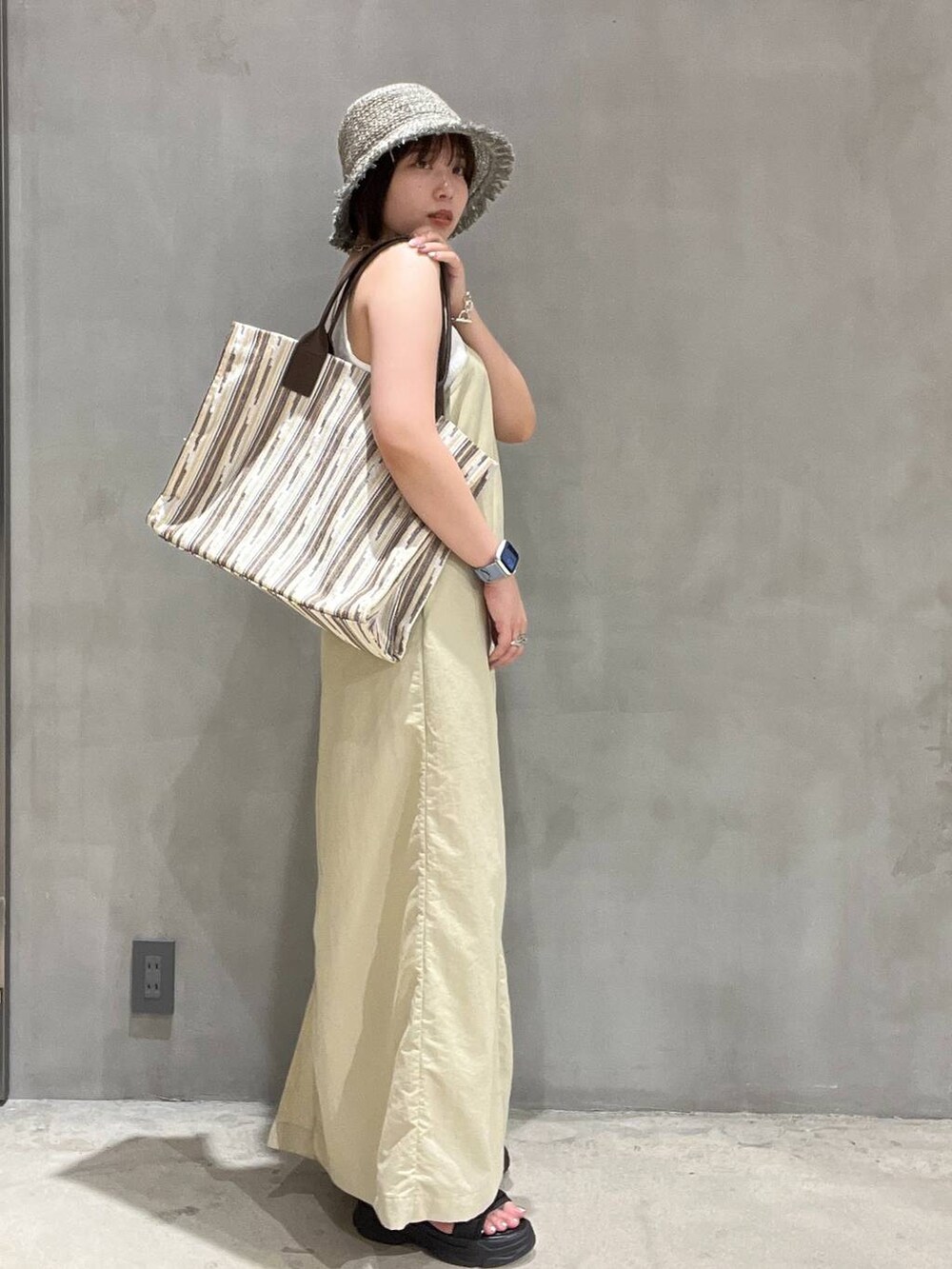 ブラック系のサンダル、ベージュ系のワンピース、ブラウン系のトートバッグを着用したレディースの夏コーディネートの2枚目の写真