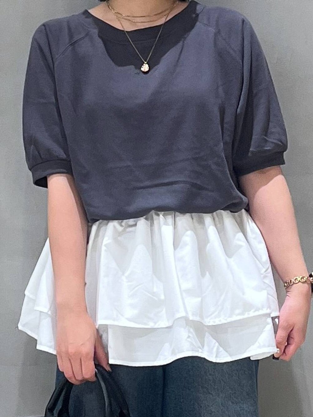 ブルー系のデニムパンツ、ブラック系のパンプス、ブラック系のショルダーバッグを着用したレディースの夏コーディネートの4枚目の写真