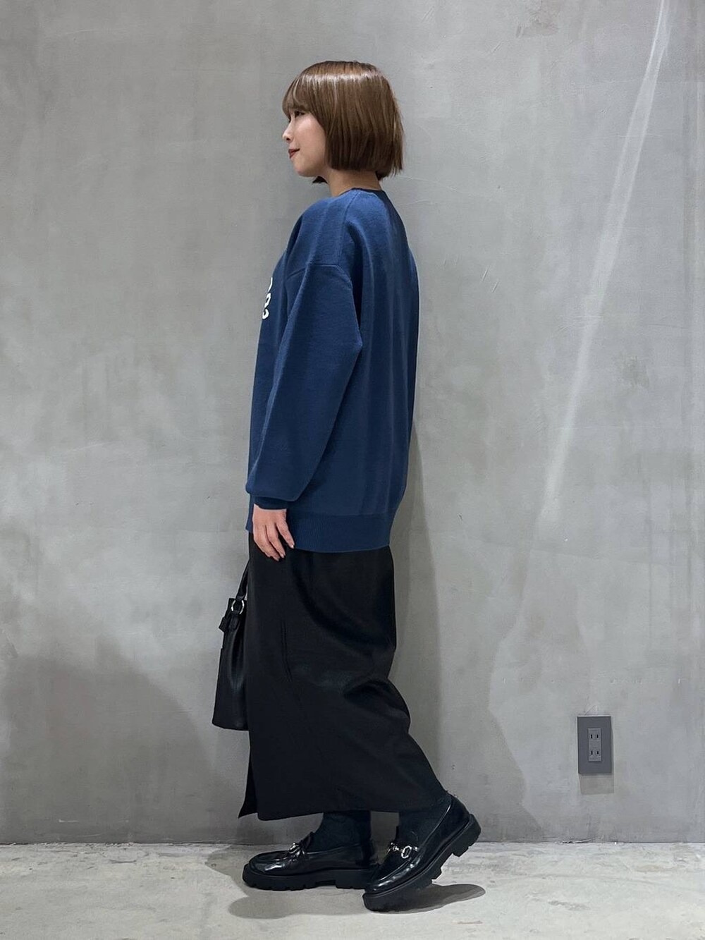 ブラック系のスカート、ブラック系のショルダーバッグ、ブルー系のニット/セーターを着用したレディースの冬コーディネートの2枚目の写真