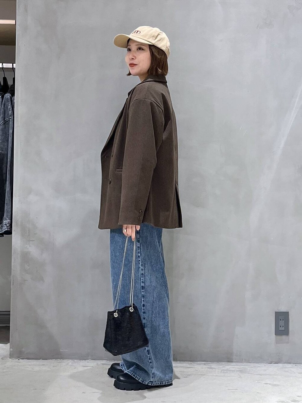ブルー系のデニムパンツ、ブラック系のブーツ、ブラウン系のテーラードジャケットを着用したレディースの秋コーディネートの2枚目の写真