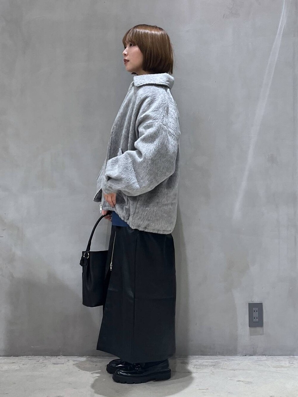 ブラック系のスカート、ブラック系のショルダーバッグ、ブルー系のニット/セーターを着用したレディースの冬コーディネートの6枚目の写真