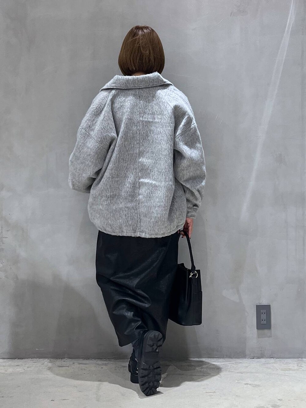 ブラック系のスカート、ブラック系のショルダーバッグ、ブルー系のニット/セーターを着用したレディースの冬コーディネートの7枚目の写真