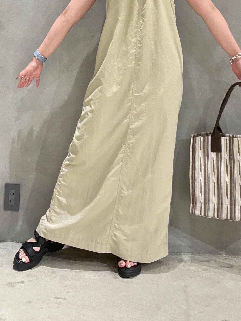 ブラック系のサンダル、ベージュ系のワンピース、ブラウン系のトートバッグを着用したレディースの夏コーディネートの3枚目の写真