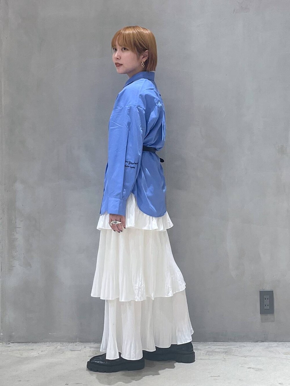 ベージュ系のスカート、ブラック系のショルダーバッグ、ブルー系のシャツ/ブラウスを着用したレディースの秋コーディネートの2枚目の写真