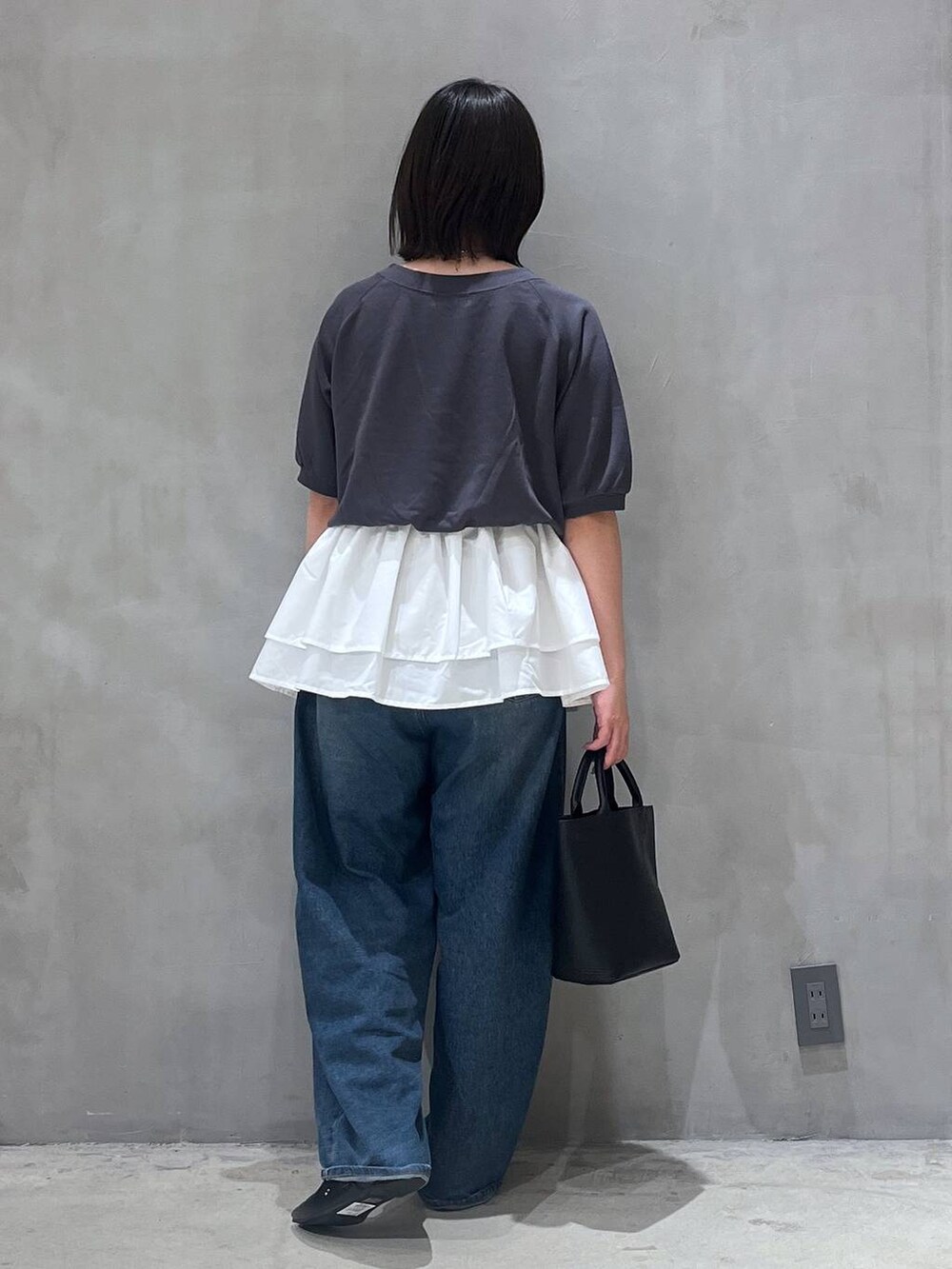 ブルー系のデニムパンツ、ブラック系のパンプス、ブラック系のショルダーバッグを着用したレディースの夏コーディネートの3枚目の写真