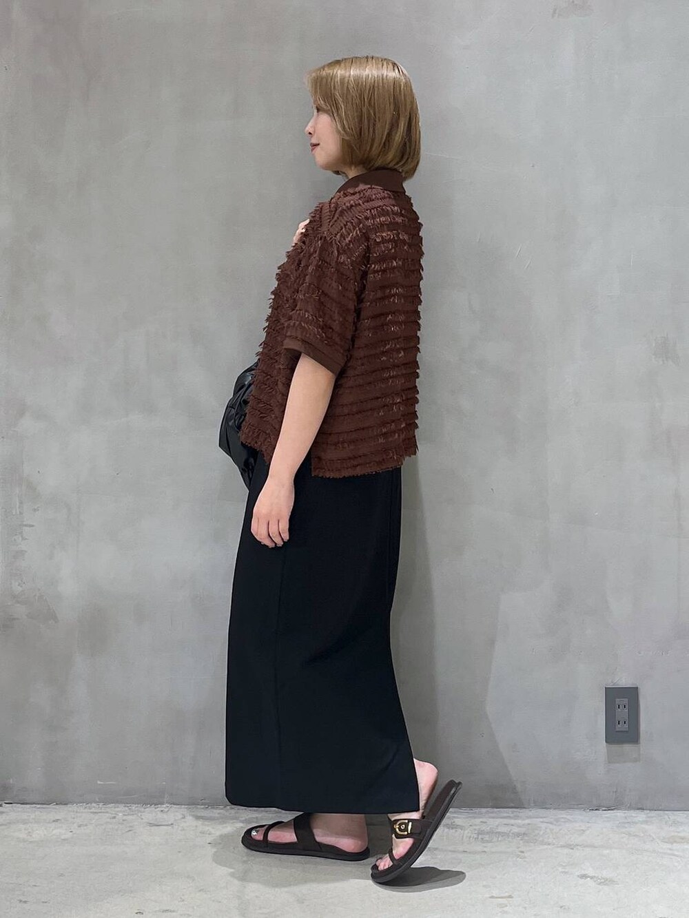 ブラック系のスカート、ブラック系のショルダーバッグ、ブラウン系のTシャツ/カットソーを着用したレディースの夏コーディネートの2枚目の写真