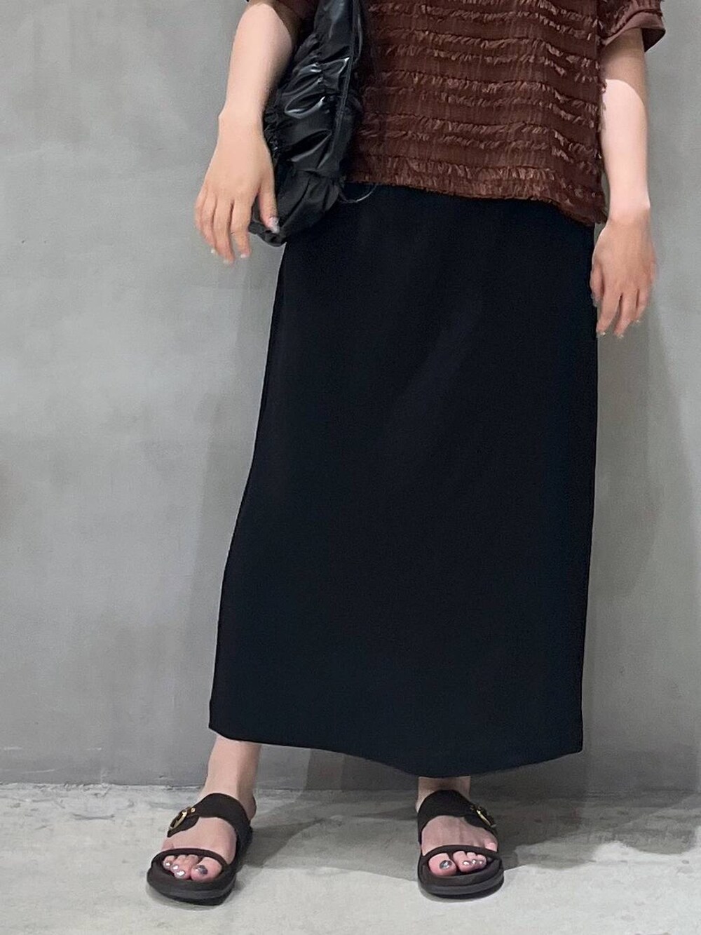 ブラック系のスカート、ブラック系のショルダーバッグ、ブラウン系のTシャツ/カットソーを着用したレディースの夏コーディネートの5枚目の写真