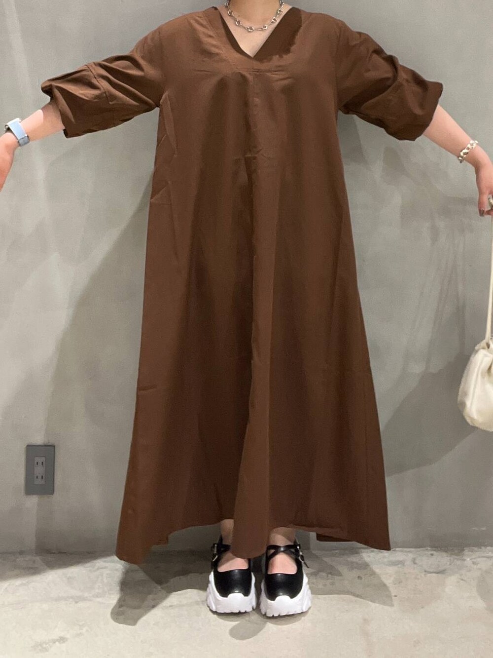 ブラック系のスニーカー、ベージュ系のショルダーバッグ、ブラウン系のワンピースを着用したレディースの夏コーディネートの4枚目の写真