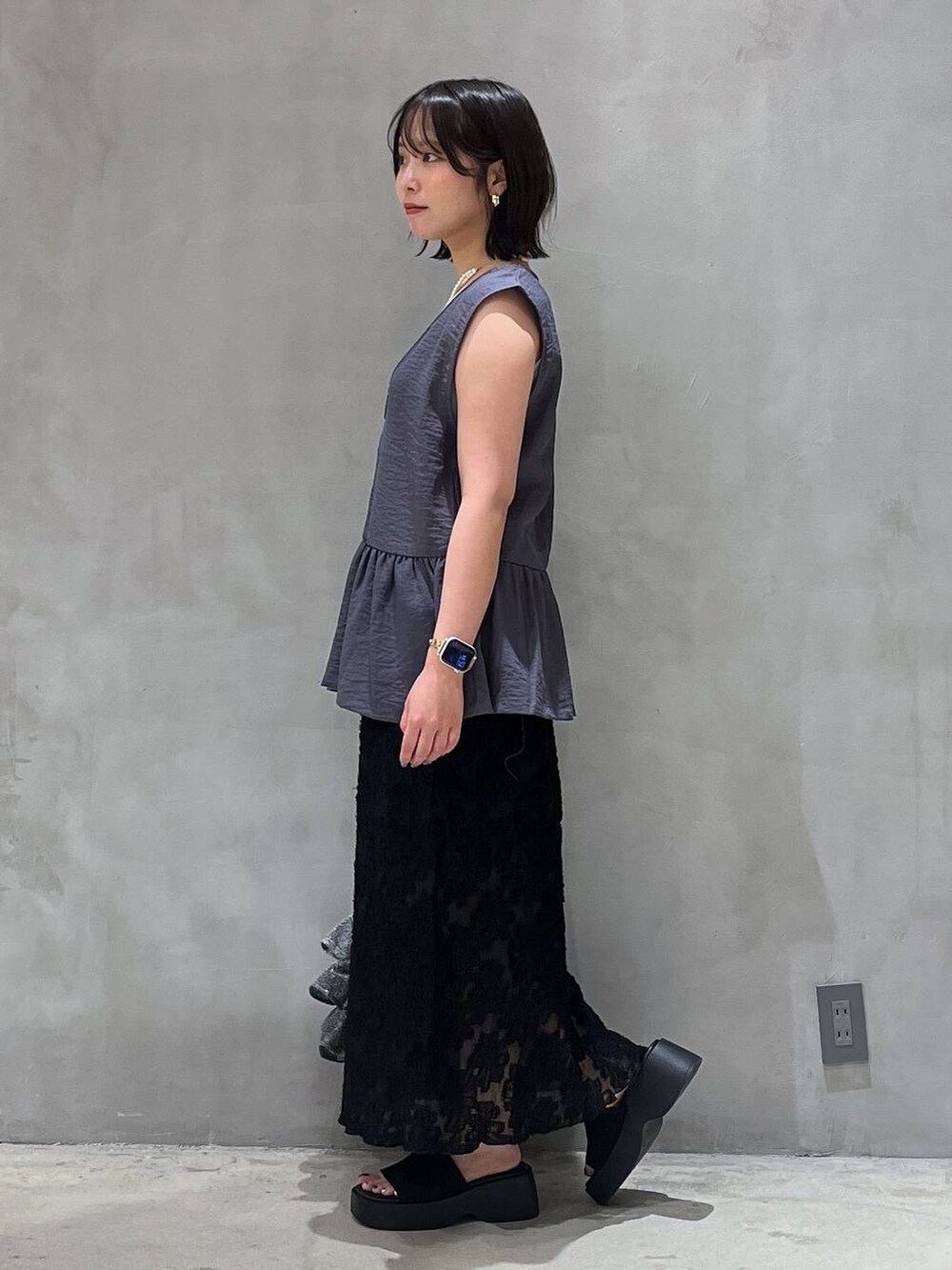 シルバー系のショルダーバッグ、ブラック系のサンダル、ブラック系のスカートを着用したレディースの夏コーディネートの3枚目の写真