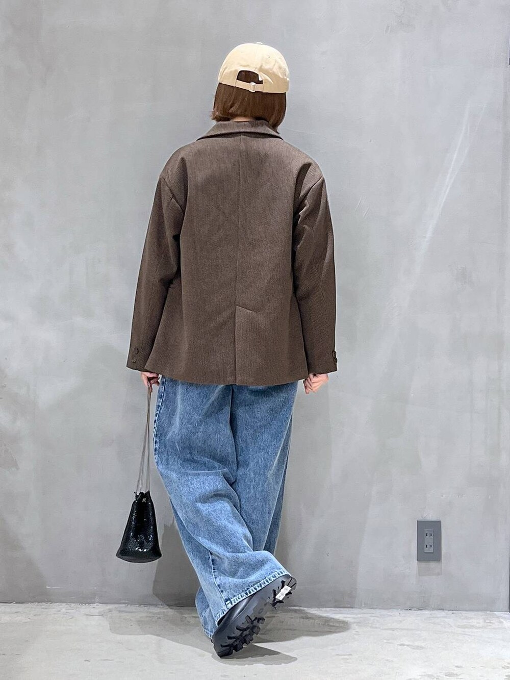 ブルー系のデニムパンツ、ブラック系のブーツ、ブラウン系のテーラードジャケットを着用したレディースの秋コーディネートの3枚目の写真