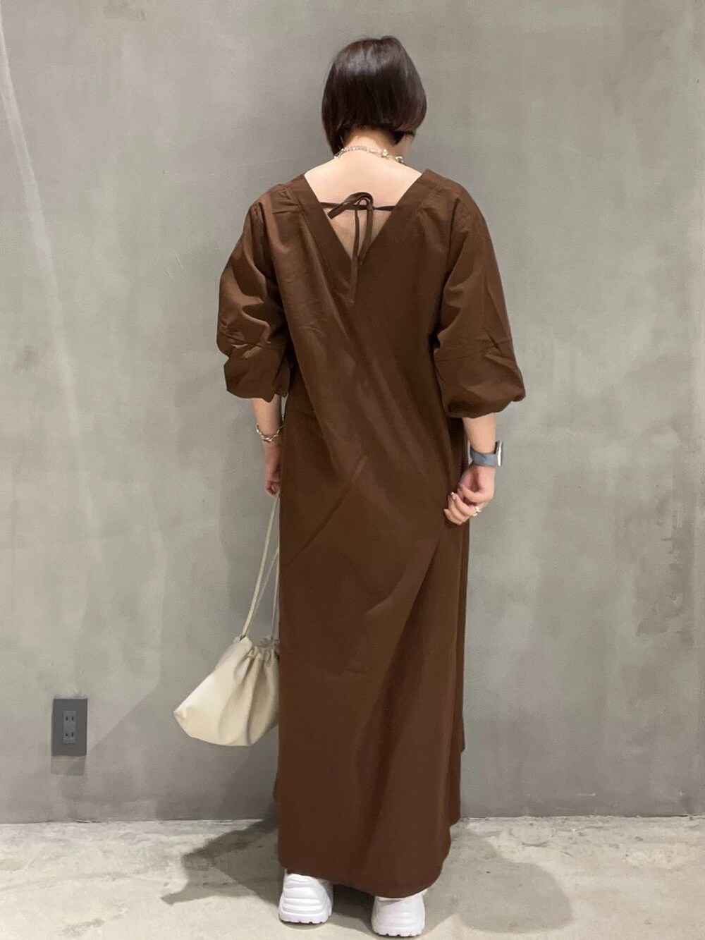 ブラック系のスニーカー、ベージュ系のショルダーバッグ、ブラウン系のワンピースを着用したレディースの夏コーディネートの3枚目の写真