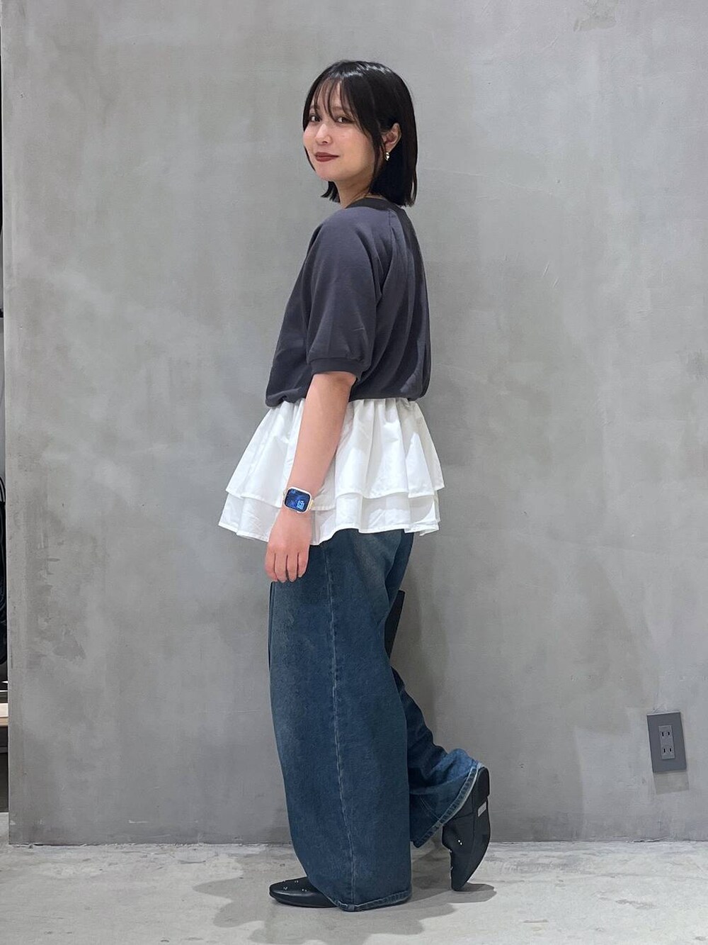 ブルー系のデニムパンツ、ブラック系のパンプス、ブラック系のショルダーバッグを着用したレディースの夏コーディネートの2枚目の写真