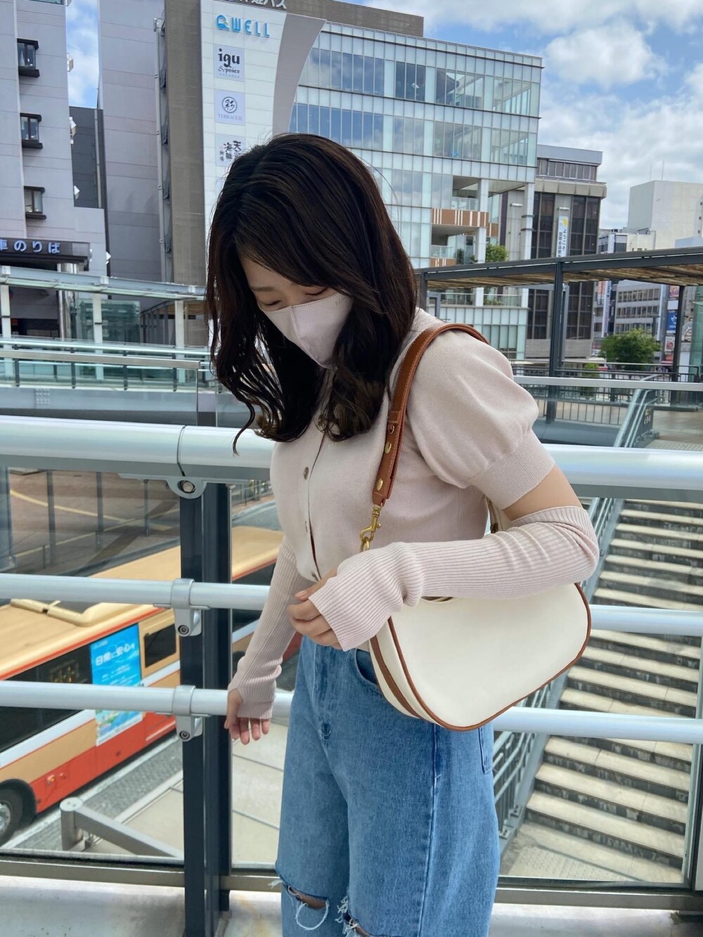 ピンク系のニット/セーター、ブルー系のデニムパンツ、ホワイト系のショルダーバッグを着用したレディースの春コーディネートの2枚目の写真