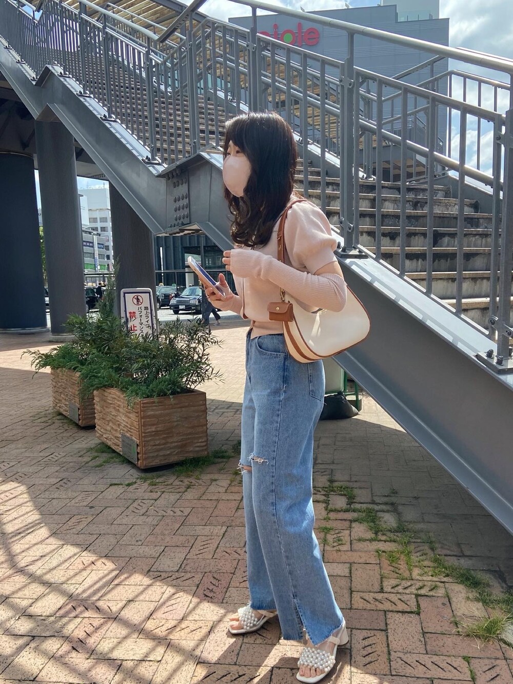 ピンク系のニット/セーター、ブルー系のデニムパンツ、ホワイト系のショルダーバッグを着用したレディースの春コーディネートの3枚目の写真