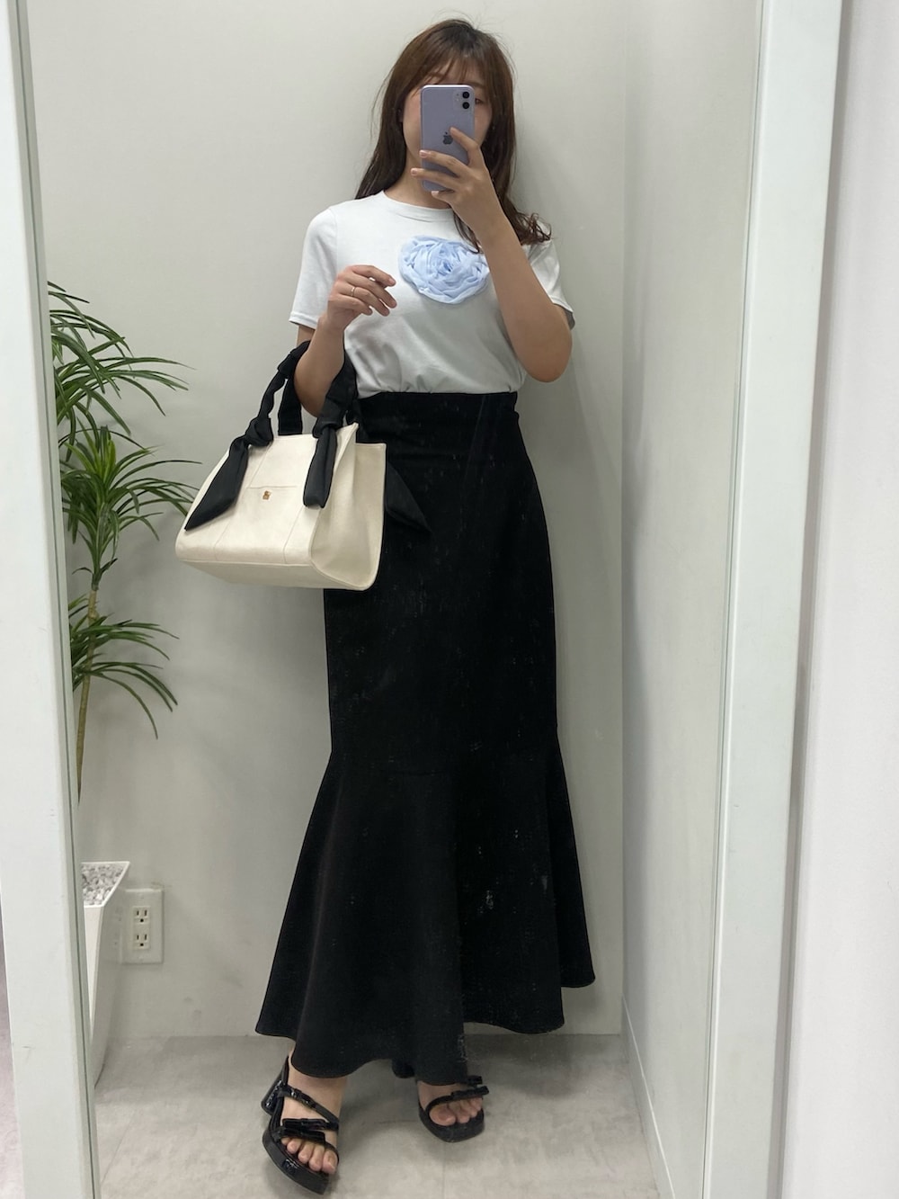 ホワイト系のトートバッグ、シルバー系のサンダル、ブラック系のスカートを着用したレディースの夏コーディネートの2枚目の写真