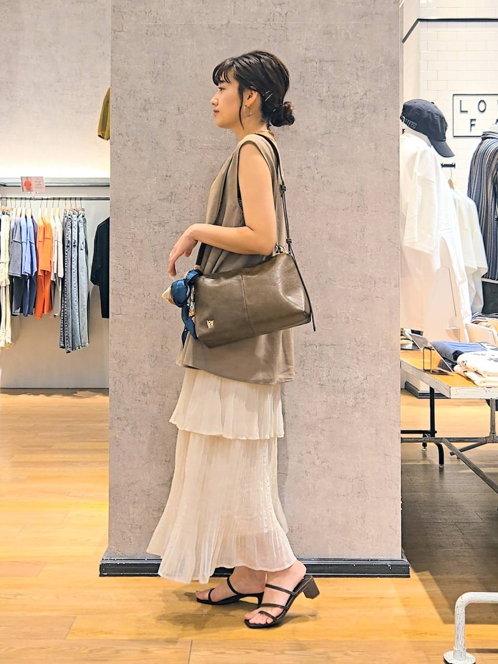 ブラック系のタンクトップ、ブラウン系のショルダーバッグ、ブラウン系のサンダルを着用したレディースの春コーディネートの3枚目の写真