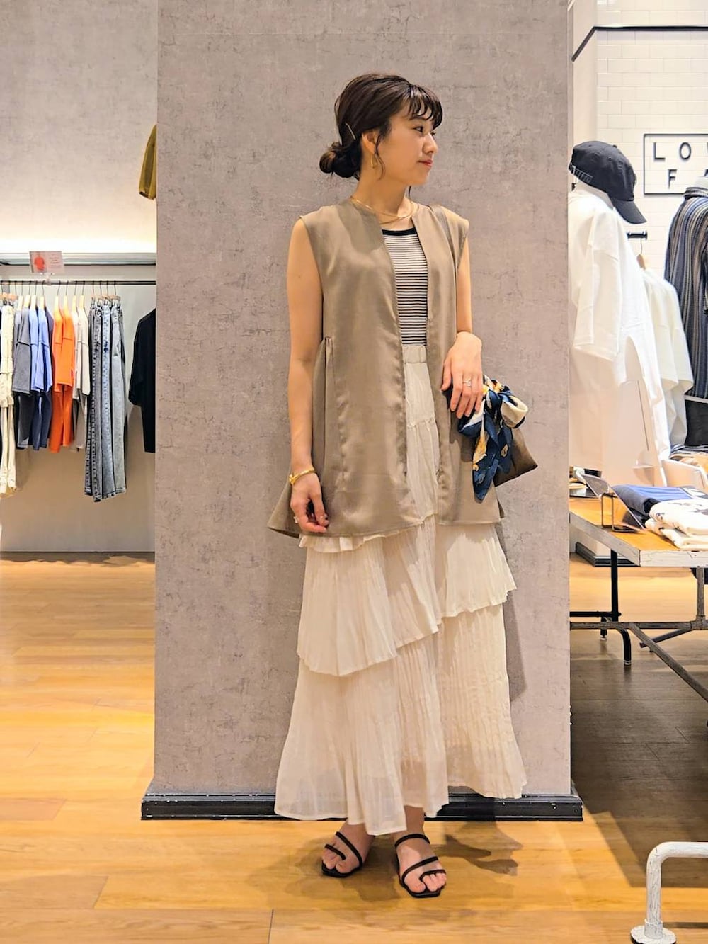 ブラック系のタンクトップ、ブラウン系のショルダーバッグ、ブラウン系のサンダルを着用したレディースの春コーディネートの2枚目の写真