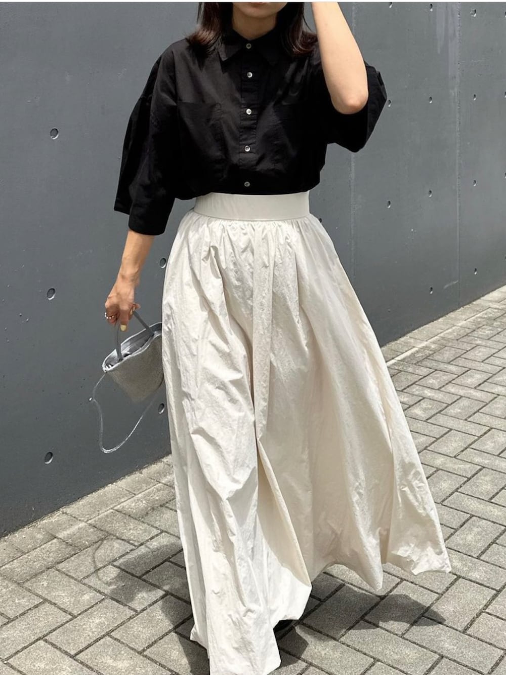 ホワイト系のスカート、ブラック系のシャツ/ブラウス、ブラック系のサンダルを着用したレディースの夏コーディネートの3枚目の写真