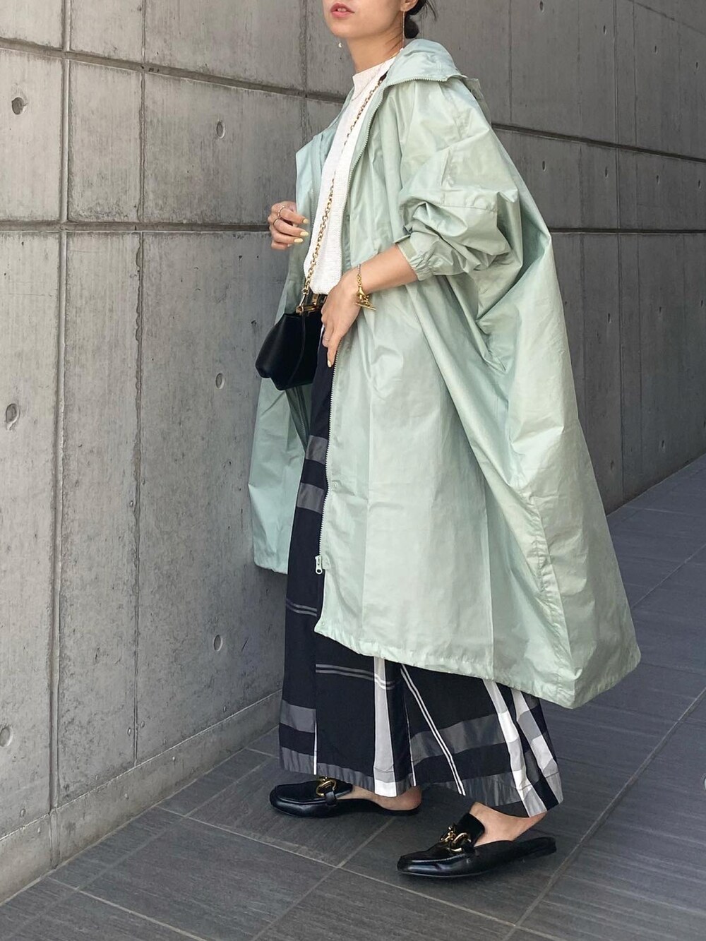 ブラック系のハンドバッグ、ブラック系のスカート、ブラック系のシューズを着用したレディースの春コーディネートの2枚目の写真