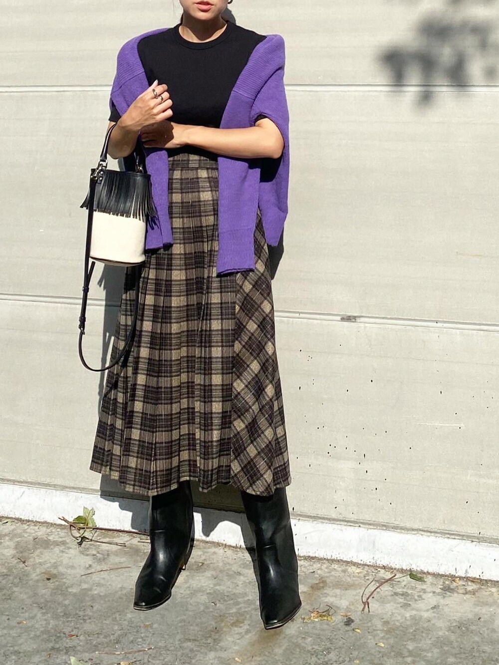 グレー系のスカート、ブラック系のブーツ、ホワイト系のバッグを着用したレディースの秋コーディネートの4枚目の写真