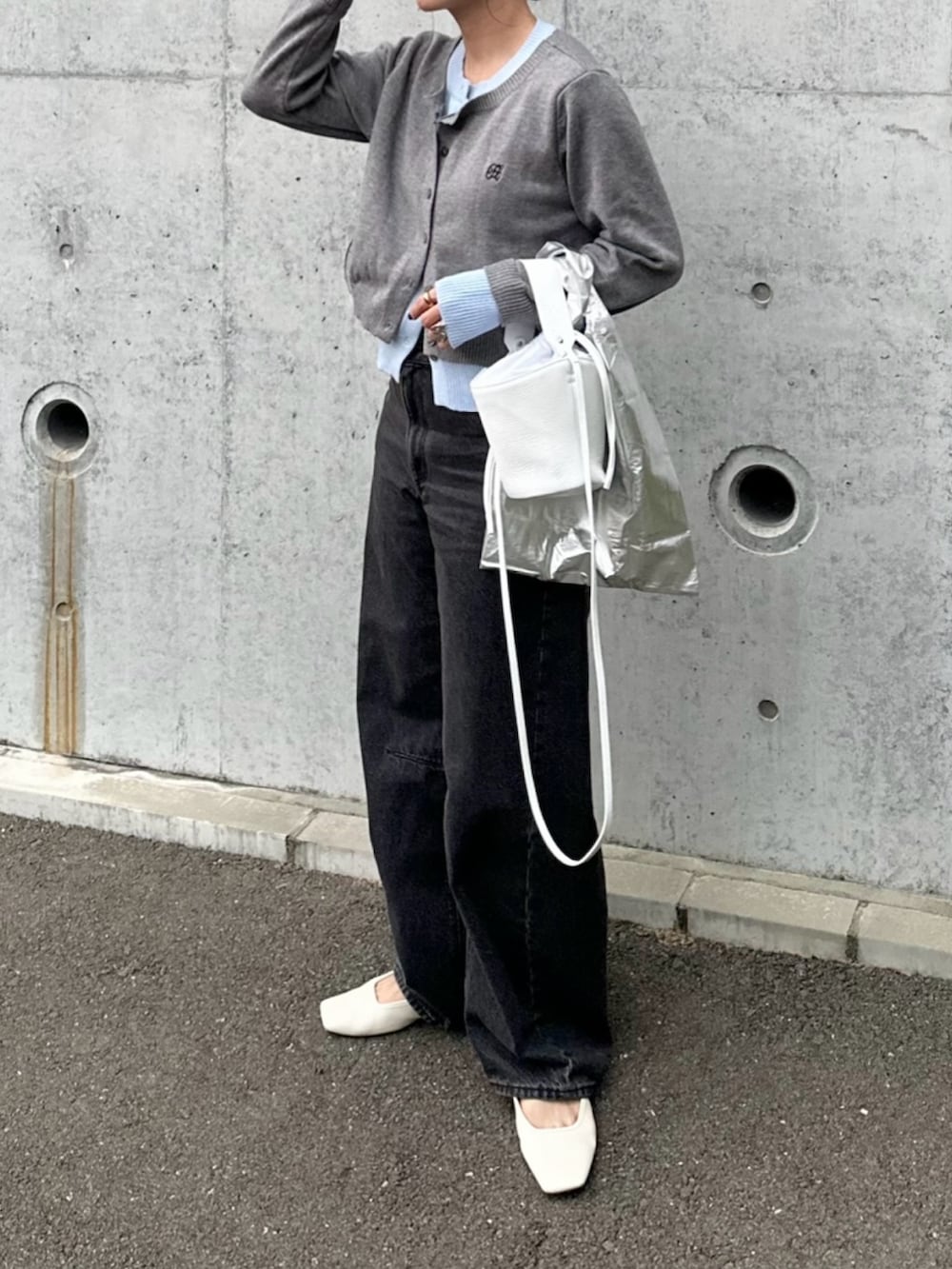 ブラック系のデニムパンツ、ホワイト系のシューズ、グレー系のカーディガン/ボレロを着用したレディースの秋コーディネートの2枚目の写真