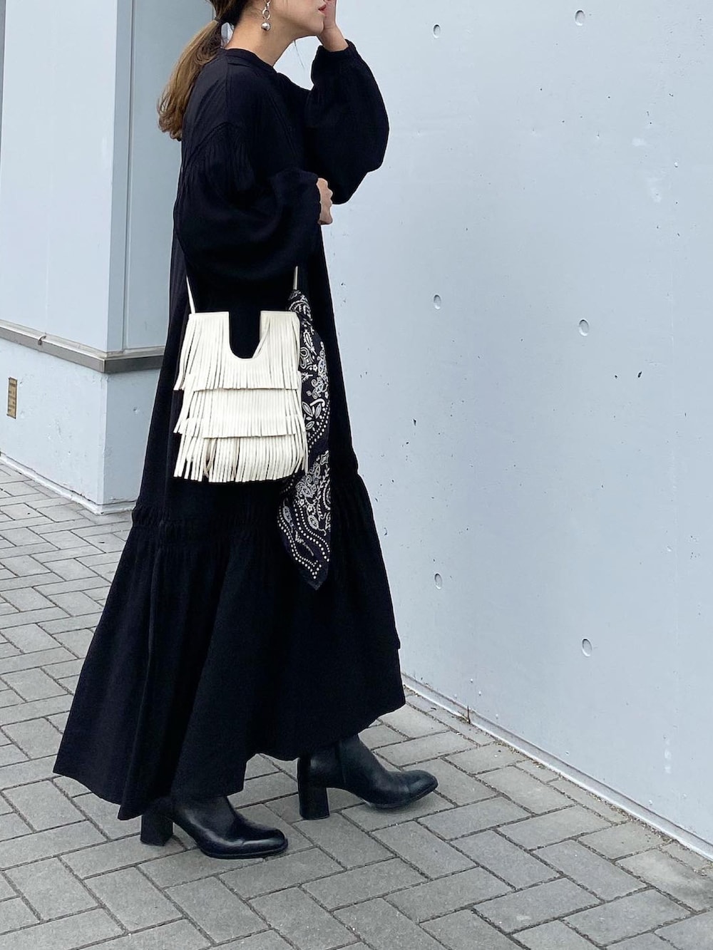 ブラック系のブーツ、ブラック系のワンピース、ホワイト系のショルダーバッグを着用したレディースの秋コーディネートの2枚目の写真