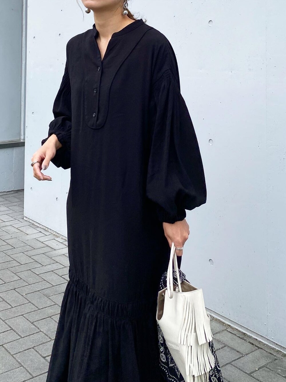 ブラック系のブーツ、ブラック系のワンピース、ホワイト系のショルダーバッグを着用したレディースの秋コーディネートの5枚目の写真