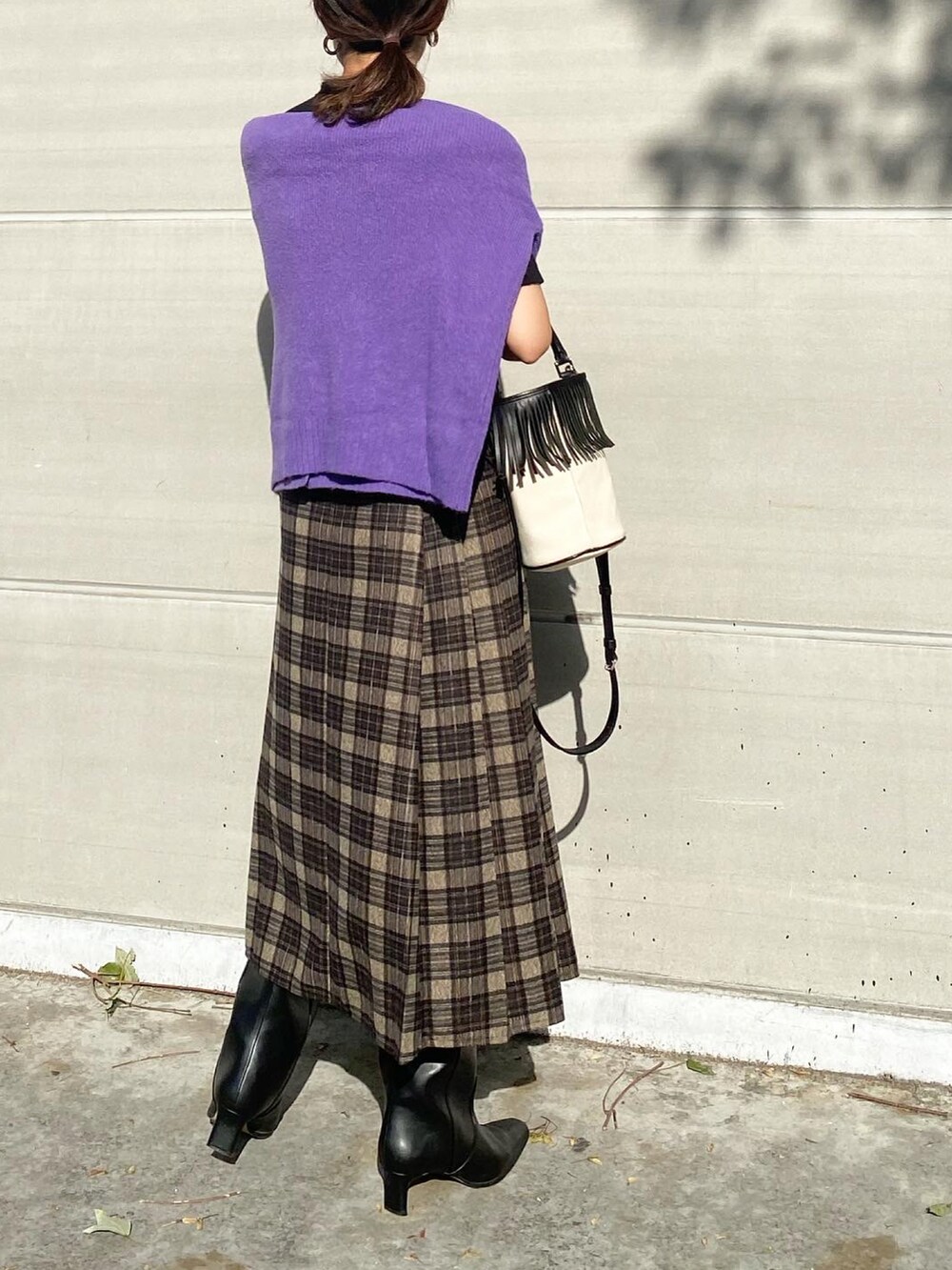 グレー系のスカート、ブラック系のブーツ、ホワイト系のバッグを着用したレディースの秋コーディネートの2枚目の写真